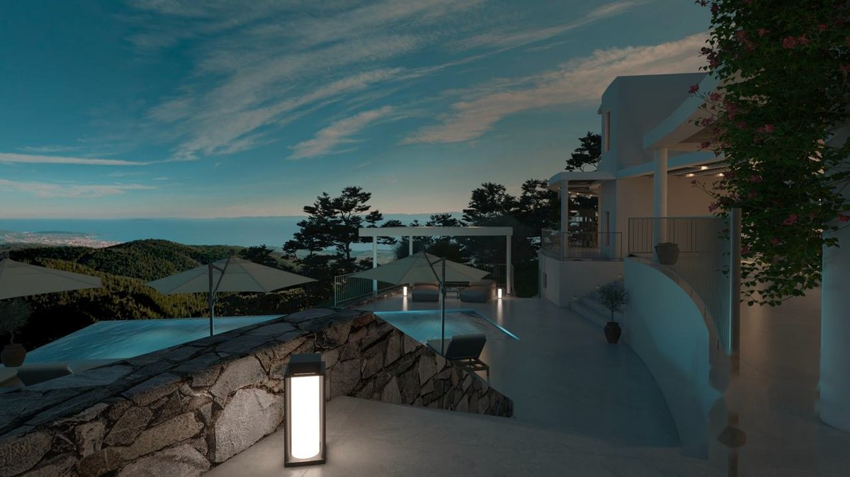 Covered outdoor kitchen with stone wall, grill and bar seating at the villa
