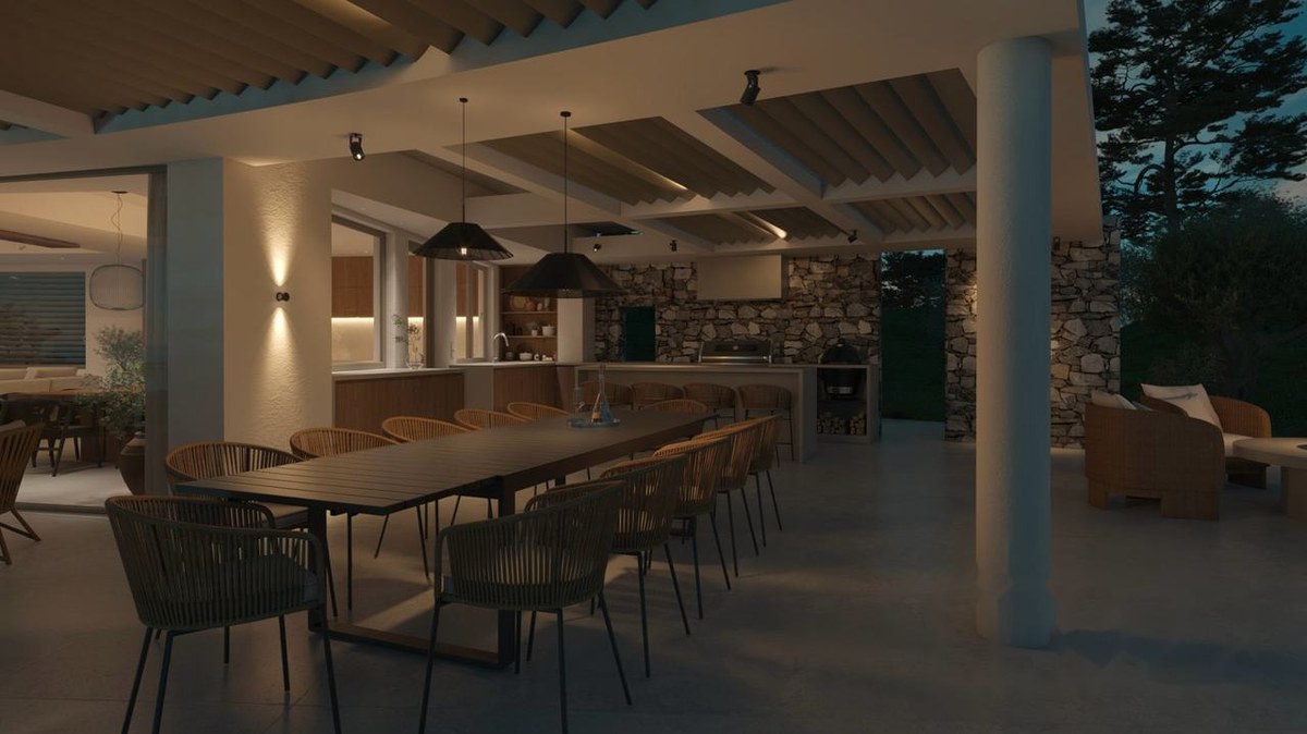 Covered outdoor dining room and summer kitchen lit at dusk in a luxury Greek villa by Akra Vista